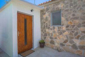 ein Steingebäude mit einer Holztür und einer Pflanze in der Unterkunft Family friendly house with a swimming pool Vadalj, Primosten - 21379 in Vadalj