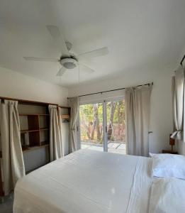 a bedroom with a white bed and a ceiling fan at Casa Mariposa in Tola