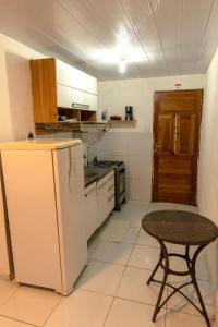 a small kitchen with a table and a refrigerator at Noronha Economy Suítes - Hospedagem com melhor localização e custo benefício da ilha in Fernando de Noronha