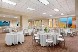 um salão de banquetes com mesas e cadeiras brancas em Sheraton Raleigh Hotel em Raleigh