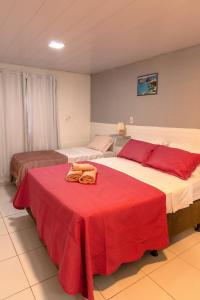 two beds in a room with a red blanket on a table at Noronha Economy Suítes - Hospedagem com melhor localização e custo benefício da ilha in Fernando de Noronha