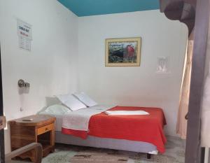 a bedroom with a bed with a red blanket at Hostal Brisas Del Mar in Puerto Villamil