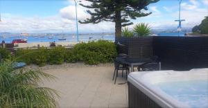 uma varanda com uma mesa e cadeiras e uma banheira em The Bay The Beach The Mount The Best em Mount Maunganui