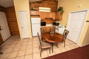 a kitchen with a table and chairs and a white refrigerator at Cabin Close to parkway rd with River View in Pigeon Forge