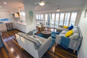 a living room with two couches and a kitchen at Happy Tides in Beachmere