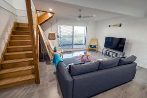 a living room with a blue couch and a staircase at Happy Tides in Beachmere