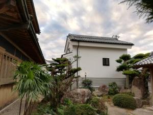 ein Gebäude in einem Garten mit Felsen und Bäumen in der Unterkunft くまの蔵inn Warehouse in Shingu