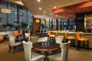 un restaurante con mesas y sillas y un bar en Sheraton Charlotte Airport en Charlotte