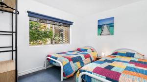 Un dormitorio con dos camas y una ventana. en Roweshaven Amazing Views, Close To Beach Accom Holidays, en Terrigal