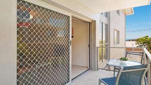 a glass screen door on a balcony with a table and chairs at Yarrara #6 Short Walk To Beach, Shops, Cafes Accom Holidays in Terrigal