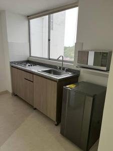 uma pequena cozinha com um lavatório e uma janela em Urban 102 em Manizales