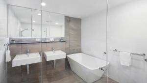 a bathroom with two sinks and a bath tub at Oceans Edge #19 Short Walk To Beach , Shops and Cafes Accom Holidays in Terrigal