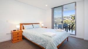 a bedroom with a bed and a large window at Oceans Edge #19 Short Walk To Beach , Shops and Cafes Accom Holidays in Terrigal
