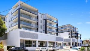 an apartment building with cars parked in front of it at Oceans Edge #19 Short Walk To Beach , Shops and Cafes Accom Holidays in Terrigal