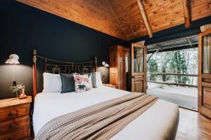 Eurunderee的住宿－The Gully - Dreamy Cabin on Acres of Outback Charm，一间卧室设有一张大床和木制天花板
