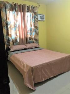 a bedroom with a bed with pink sheets and curtains at Affordable Whole House Rent Transient in Butuan