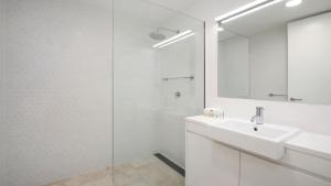 a white bathroom with a sink and a mirror at Rockpool #2 Short Walk To Beach, Shops, Cafes Accom Holidays in Terrigal +3 photos