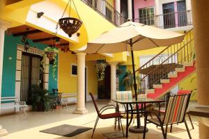 a table and chairs with an umbrella in front of a building at Hotel Guaranducha Inn in Campeche
