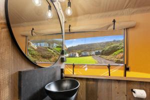 La salle de bains est pourvue d'un miroir, d'un lavabo noir et d'une fenêtre. dans l'établissement BIG4 Apollo Bay Pisces Holiday Park, à Apollo Bay