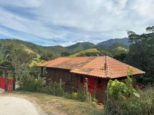 a small house with a tile roof on a mountain at Chalé da Conquista in Visconde De Maua