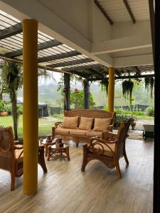 eine Terrasse mit Sofas und Stühlen auf einem Holzboden in der Unterkunft Habitaciones con Baño privado - Finca Valentina in Anolaima