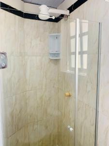 um chuveiro com uma porta de vidro na casa de banho em Suite familiar completa em Búzios