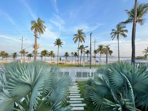 uma vista para a praia e palmeiras em SAL di Mare Hotel Boutique - Frente ao Mar com Piscina no Guarujá