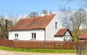 a white house with a red roof behind a fence at 3 Bedroom Nice Home In Stare Kawkowo in Stare Kawkowo