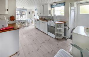 cocina con armarios blancos y suelo de madera en Amazing Home In Vstra Karup With Wifi, en Västra Karup
