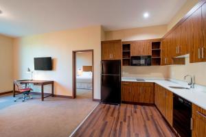 a kitchen with a black refrigerator and a table at Four Points by Sheraton Grande Prairie in Grande Prairie