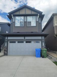 una casa con dos puertas de garaje y un cubo de basura en Cozy Springs, en Calgary