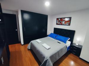 um quarto com uma cama grande e almofadas azuis em Céntrico luminoso y equipado apto em Pasto