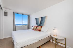 a white bedroom with a bed and a window at *Remodeled Oceanfront in Waikiki - Ilikai Marina in Honolulu