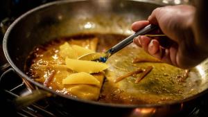 a person stirring a pot of food with a spoon at InterContinental Bangkok by IHG in Bangkok