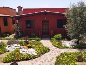 una casa roja con un jardín de flores delante de ella en Villas Rincón del Paraíso, en Las Palmas