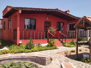 una casa roja con un jardín delante en Villas Rincón del Paraíso, en Las Palmas