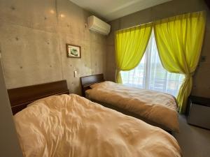 um quarto com 2 camas e uma janela com cortinas amarelas em Ｂ＆ＢTandem em Ginoza