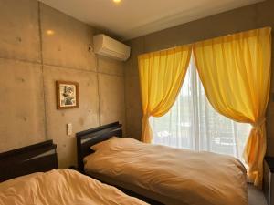 宜野座的住宿－Ｂ＆ＢTandem，一间卧室设有床和黄色窗帘的窗户