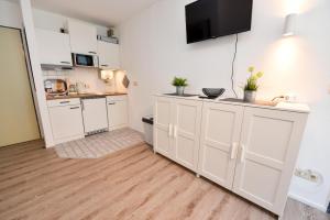 cocina con armarios blancos y TV en la pared en Appartementhaus "Pavillon" Appartement PAV06, en Döse