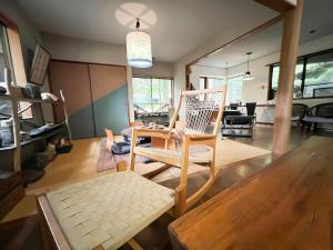 uma sala de estar com uma cadeira de baloiço e uma mesa em 貸別荘・グランピングひめしゃら em Kirishima