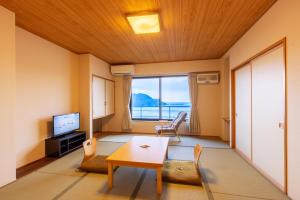 a living room with a table and a tv at Ofunato Onsen in Ōfunato