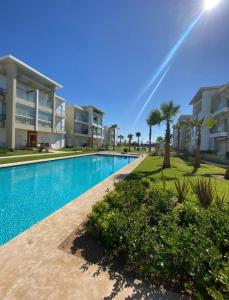 a swimming pool in front of a building with palm trees at CASA BAY BEACH OMK 2 in Sidi Rahal