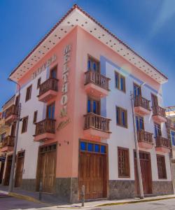 - un bâtiment rose avec des portes et des balcons en bois dans l'établissement Hotel Melthon Class, à Ayacucho