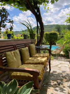 un banco de madera con almohadas en el patio en La Belle Demeure en Saint-Cybranet