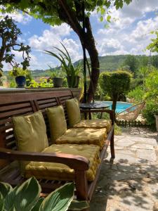 un banco de madera con almohadas en el patio en La Belle Demeure proche Sarlat, en Saint-Cybranet