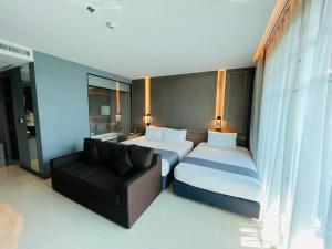een hotelkamer met 2 bedden en een bank bij Mandarin Eastville, Pattaya - SHA Extra Plus in Noord Pattaya