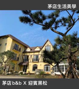 uma casa com um pinheiro em frente em 茅店BnB em Beipu