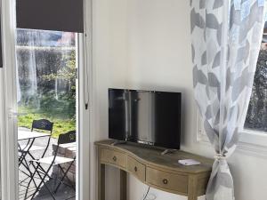une télévision sur une table en bois à côté d'une fenêtre dans l'établissement Guestroom Épinal, 1 pièce, 2 personnes - FR-1-589-473, à Épinal