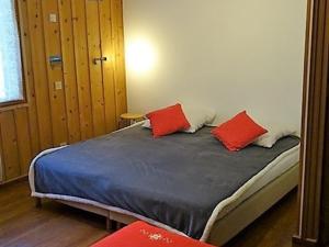 a bedroom with a bed with two red pillows on it at Chalet Cohennoz, 4 pièces, 10 personnes - FR-1-733-29 in Cohennoz