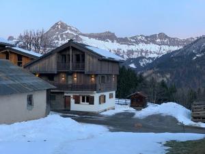 une grande maison en bois avec des montagnes enneigées en arrière-plan dans l'établissement Duplex 11 pers. au centre de Crest-Voland, cheminée, ski-room, wifi, non fumeurs - FR-1-733-36, à Crest-Voland